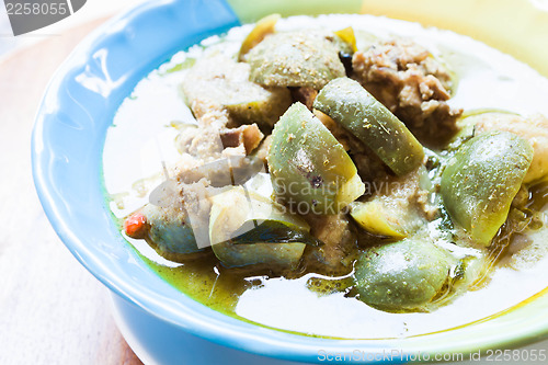 Image of A bowl of spicy green curry with chicken and eggplant
