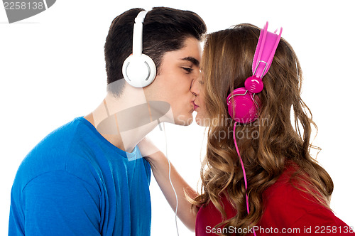 Image of Young couple enjoying music and kissing