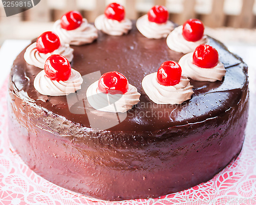 Image of Delicious chocolate cake with red cherry on top