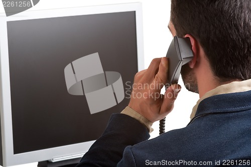 Image of Casual Businessman Talking over the Phone and Looking at a Compu