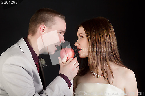 Image of young lovers woman and man biting an apple