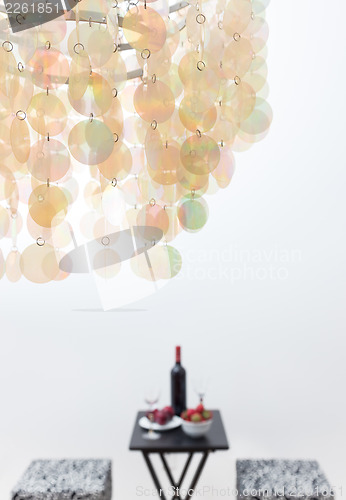 Image of Bottle of red wine on a table, beautiful chandelier decorating a