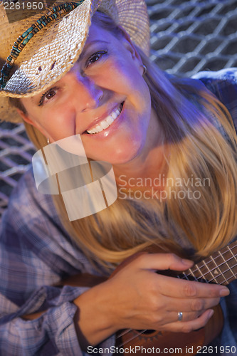 Image of Beautiful Cowgirl Near Campfire Playing Her Ukulele