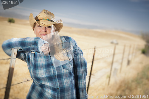 Image of Beautiful Cowgirl Against Wire Fence in Field