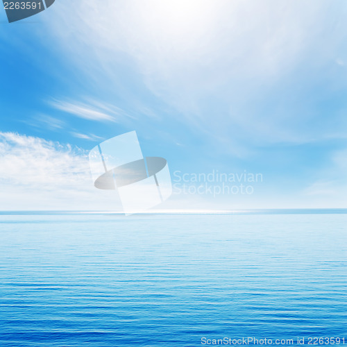 Image of light waves on blue sea and cloudy sky with sun