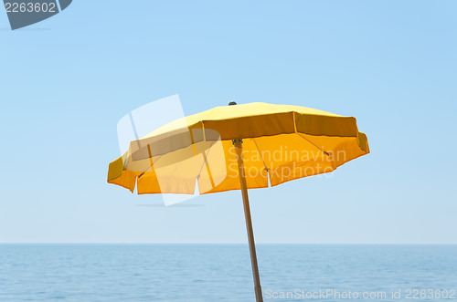 Image of yellow umbrella over sea under blue sky