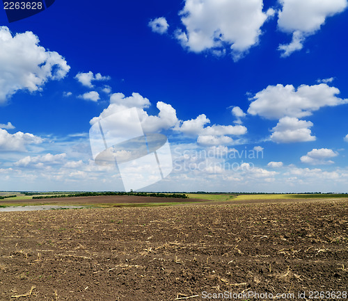 Image of cloudy sky over black field after harvesting