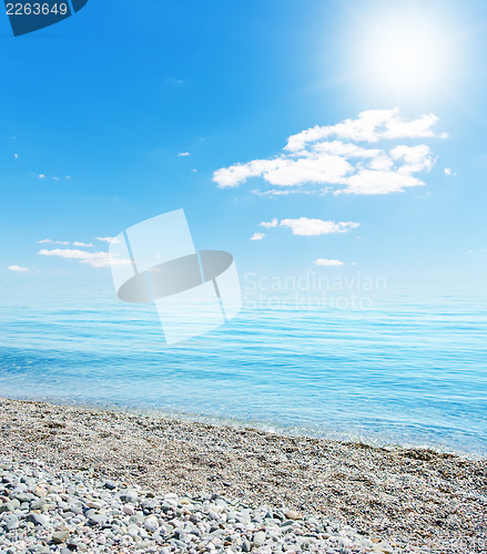 Image of sun over beach with stones