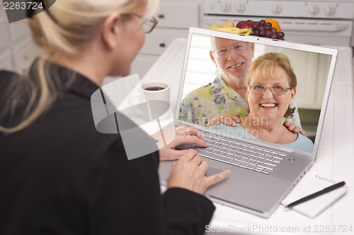 Image of Woman In Kitchen Using Laptop - Online with Senior Couple