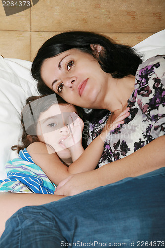 Image of beautiful young mother and her daughter on the bed