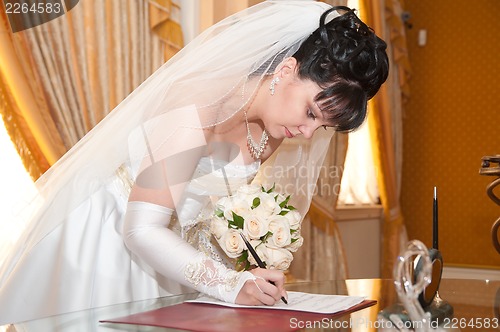 Image of Pretty bride signing document