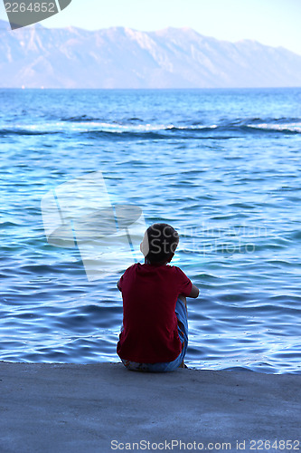 Image of Small boy sitting on the coast of Adriatic sea