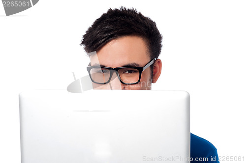 Image of Mischievous boy hiding his face with laptop