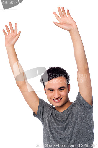 Image of Cheerful young guy raising his arms