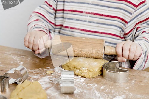 Image of child rolling dough on wooden desk