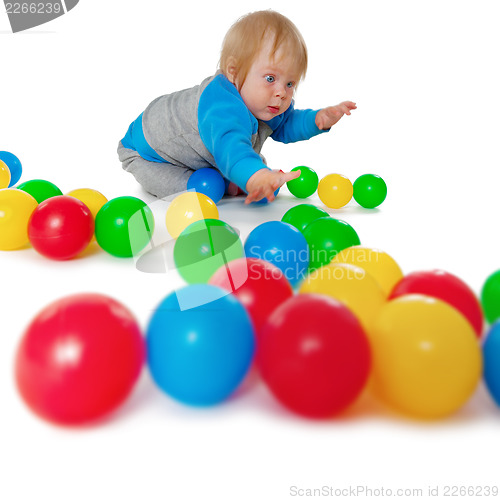 Image of Comical child playing with colored plastic balls