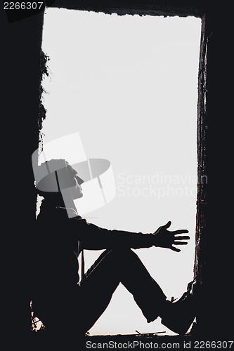 Image of Man's silhouette in the window above blue cloudy sky