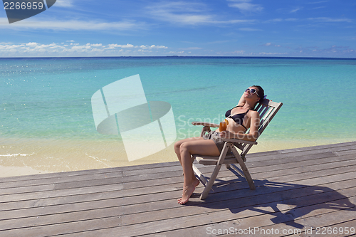 Image of Beautiful young woman with a drink by the sea