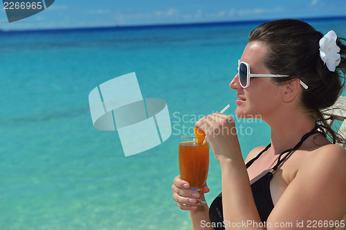 Image of Beautiful young woman with a drink by the sea