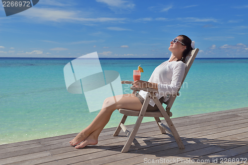 Image of Beautiful young woman with a drink by the sea