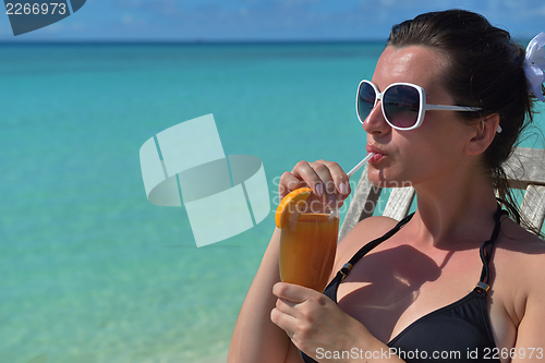 Image of Beautiful young woman with a drink by the sea