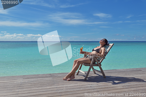 Image of Beautiful young woman with a drink by the sea