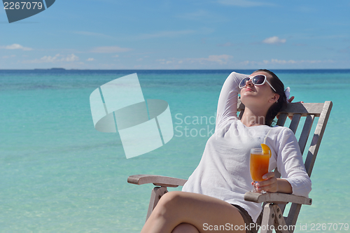 Image of Beautiful young woman with a drink by the sea