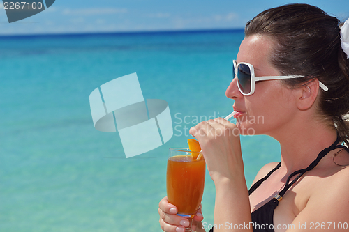 Image of Beautiful young woman with a drink by the sea