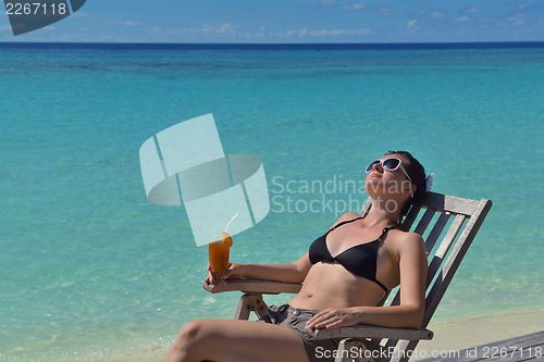 Image of Beautiful young woman with a drink by the sea