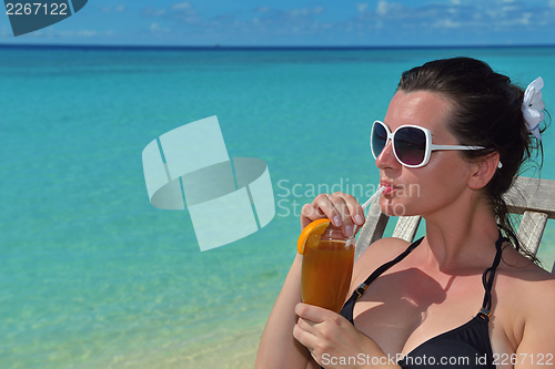 Image of Beautiful young woman with a drink by the sea