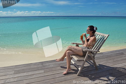 Image of Beautiful young woman with a drink by the sea