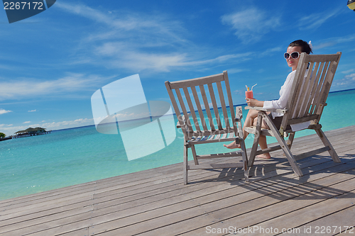 Image of Beautiful young woman with a drink by the sea