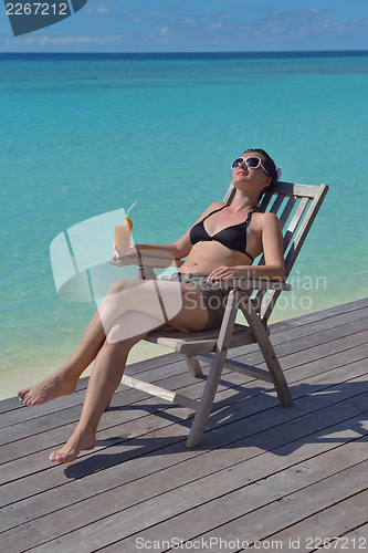 Image of Beautiful young woman with a drink by the sea