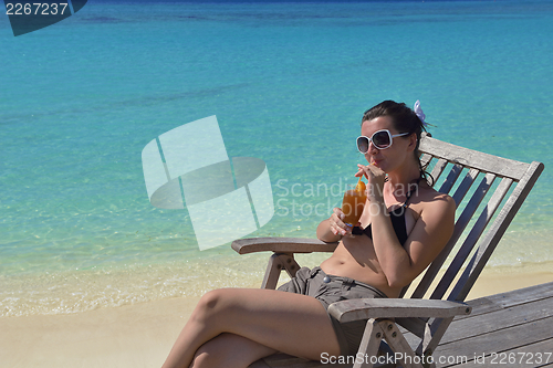 Image of Beautiful young woman with a drink by the sea