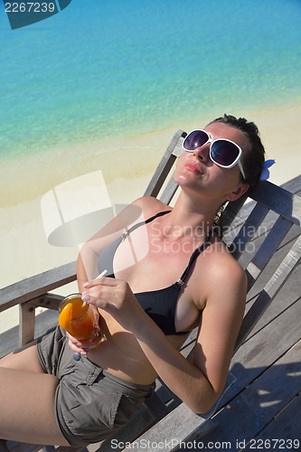 Image of Beautiful young woman with a drink by the sea