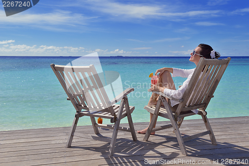 Image of Beautiful young woman with a drink by the sea