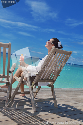 Image of Beautiful young woman with a drink by the sea