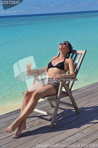 Image of Beautiful young woman with a drink by the sea