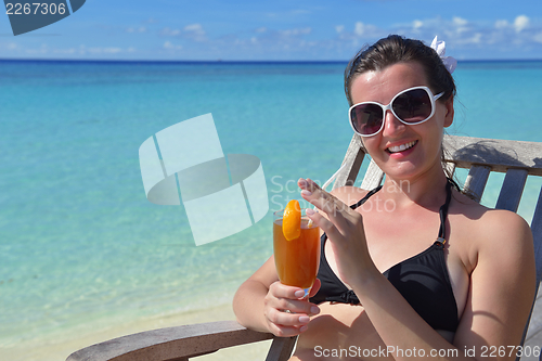 Image of Beautiful young woman with a drink by the sea