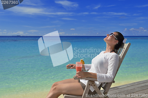 Image of Beautiful young woman with a drink by the sea