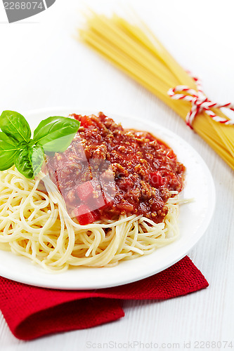 Image of Portion of spaghetti bolognese with green basil leaf on white pl
