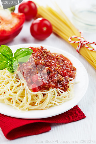 Image of Portion of spaghetti bolognese with green basil leaf on white pl