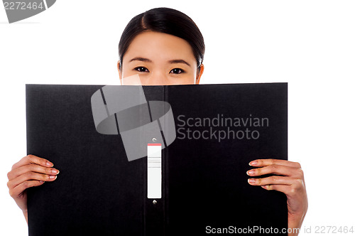 Image of Chinese woman hiding face with business file