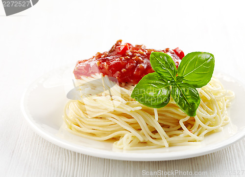 Image of Spaghetti bolognese and green basil leaf on white plate