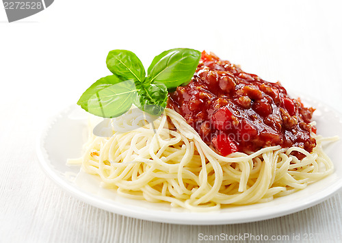 Image of Spaghetti bolognese and green basil leaf on white plate