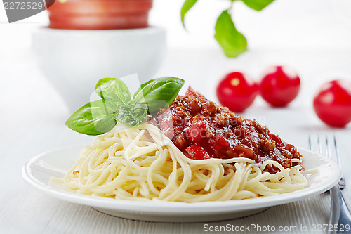 Image of Spaghetti bolognese and green basil leaf on white plate