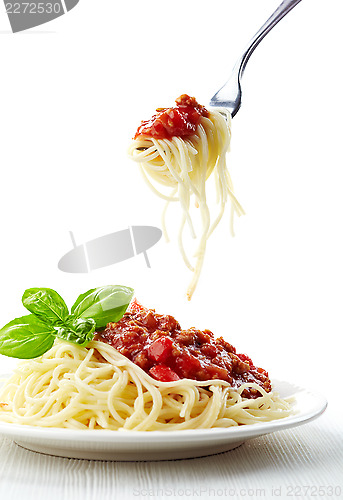 Image of Spaghetti bolognese and green basil leaf on white plate