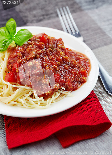 Image of Spaghetti bolognese and green basil leaf on white plate