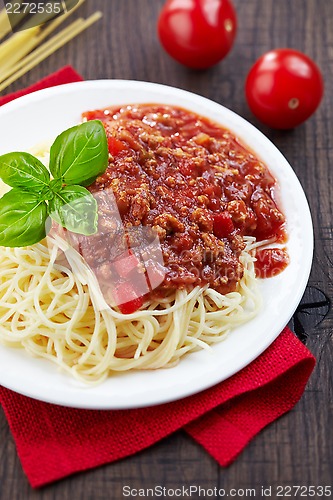 Image of Spaghetti bolognese and green basil leaf on white plate