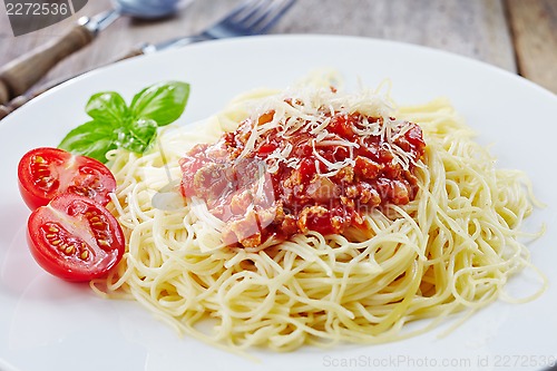 Image of Spaghetti bolognese and green basil leaf on white plate